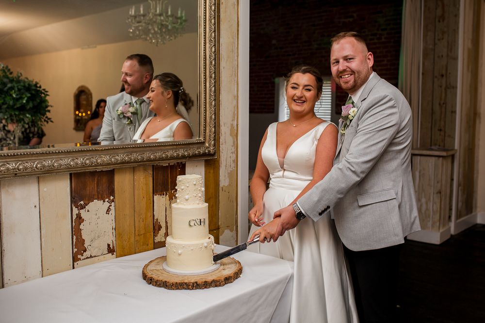 A couple shares an intimate dance at their wedding reception in an elegant venue with a chandelier and rustic decor.