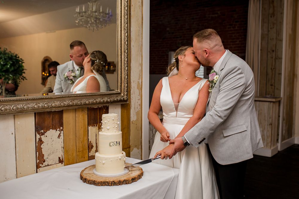 A couple embraces during their first dance at a wedding reception in a rustic brick-walled venue.