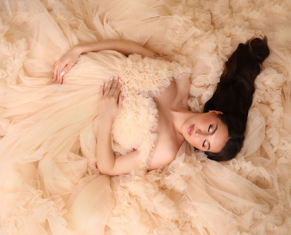 Elegant peach tulle gown spread across studio floor in romantic fashion photography.