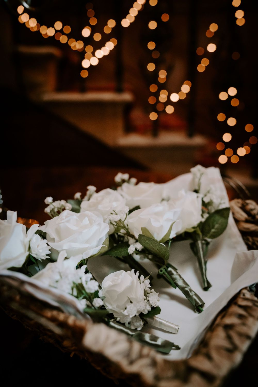 White rose boutonnieres with greenery arranged on display at wedding.