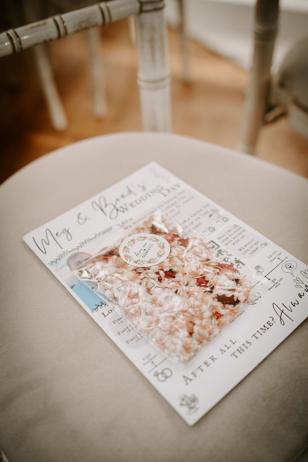 Scattered confetti and wedding invitation cards arranged on a light gray surface.