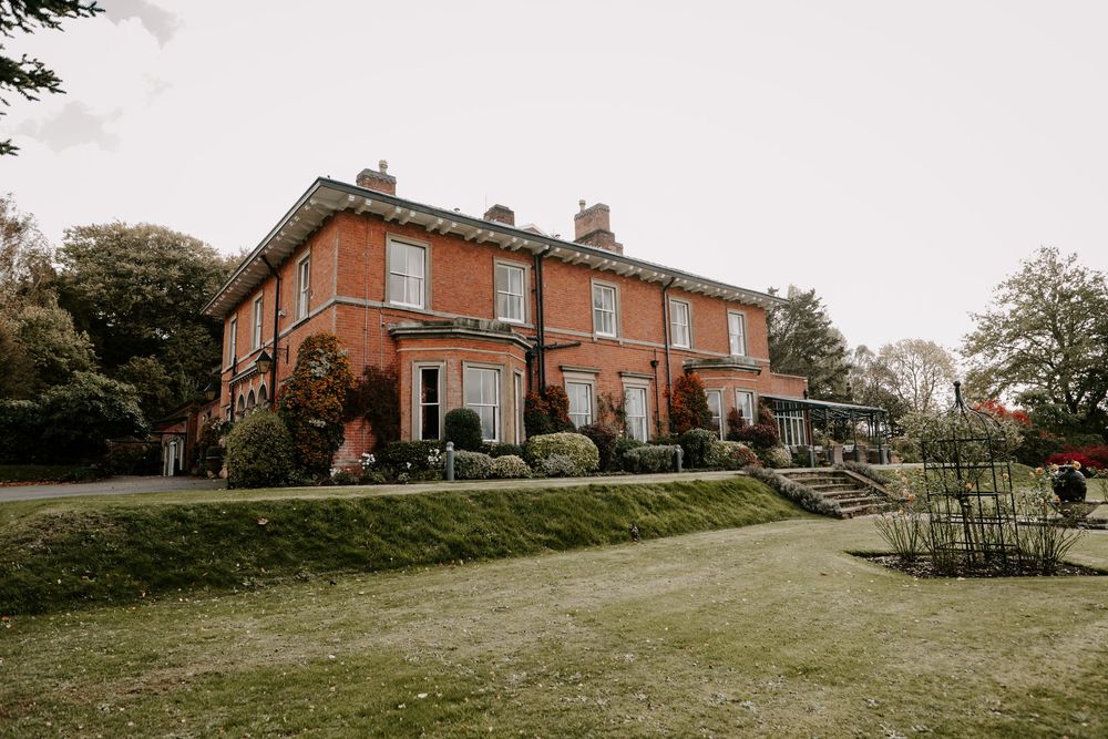 Panoramic view of rustic brick buildings and landscaped grounds at a countryside venue.