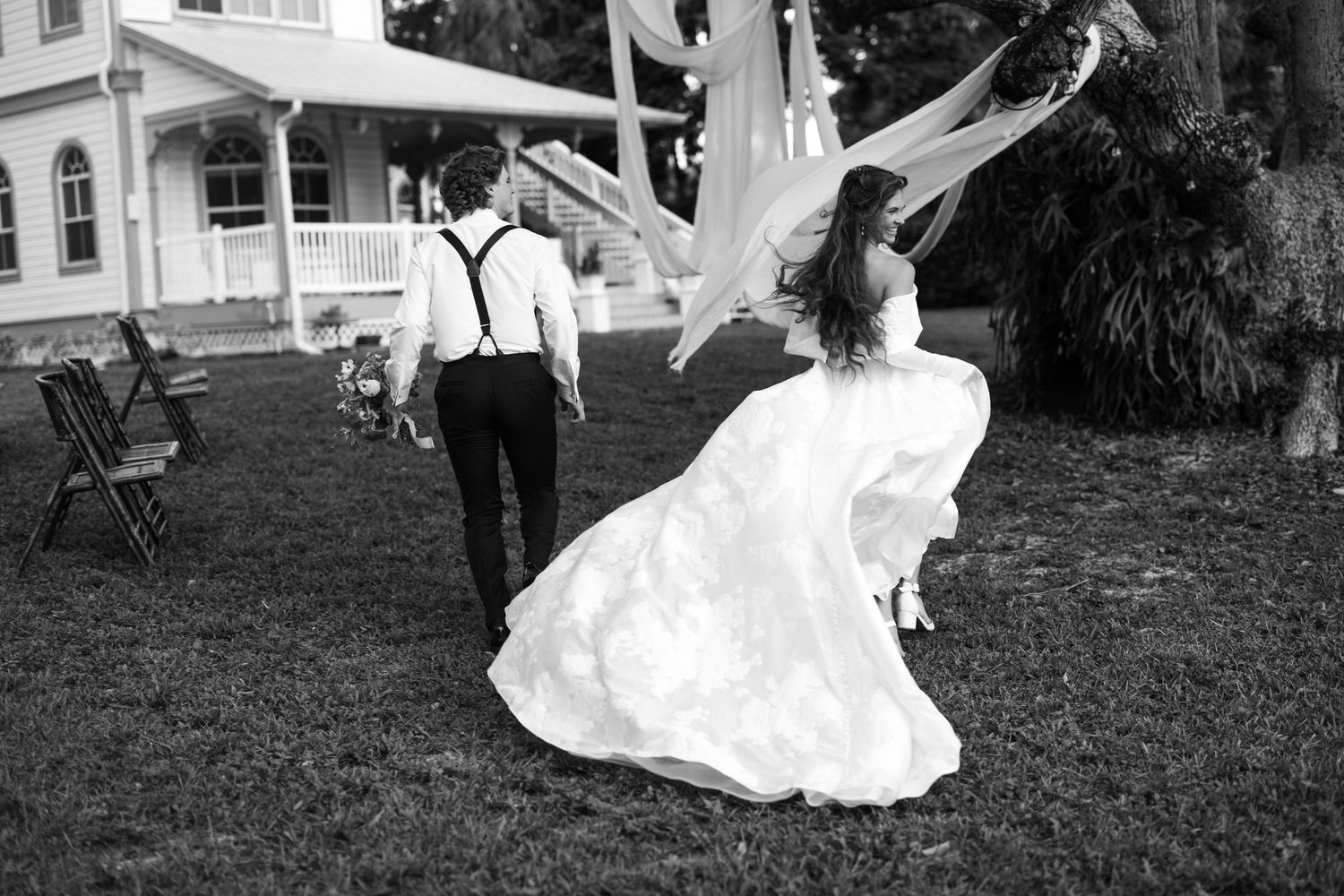 A couple in vintage wedding attire walks together joyfully at historic pioneer house that is waterfront on intercoastal in Treasure Coast FL