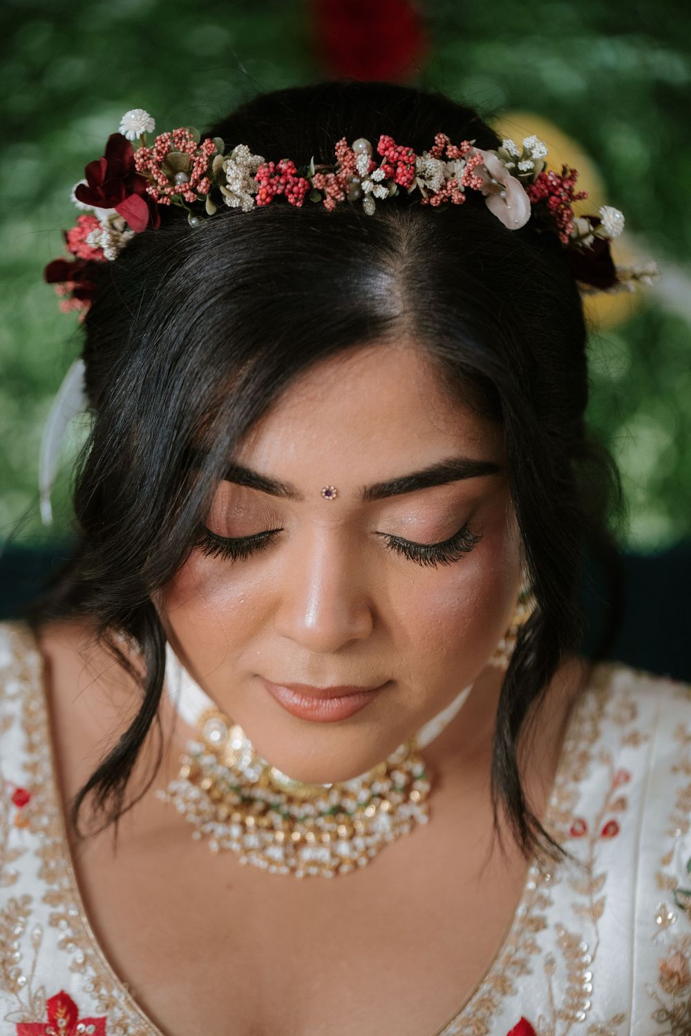Close-up portrait showing pearl jewelry and floral crown details in soft natural lighting.