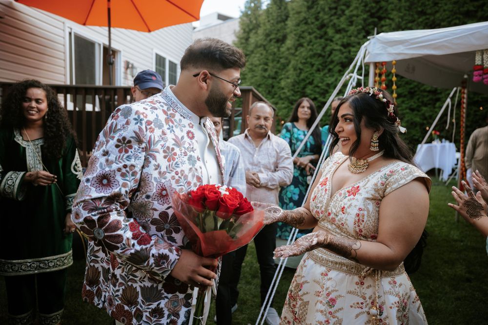 A bright orange umbrella provides shade during an outdoor summer wedding celebration.
