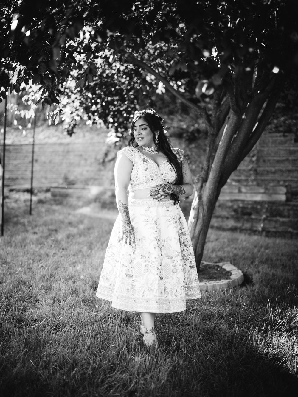 A series of four black and white photos showing a child in a white dress playing in a grassy outdoor setting.