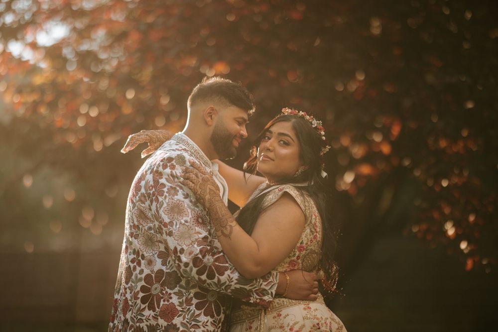 A couple shares an intimate moment during a sunset photoshoot in a romantic outdoor setting.