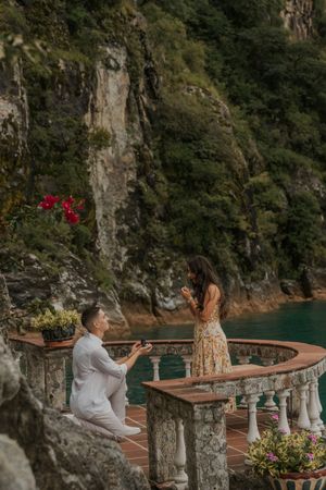 A romantic proposal moment on a scenic stone terrace overlooking turquoise waters and cliffs along the Amalfi Coast.