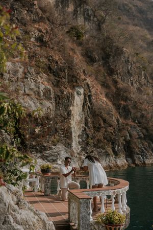 Couple shares a romantic moment on a scenic lakeside terrace surrounded by rocky mountains.
