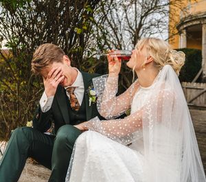 A wedding couple shares a romantic moment together outdoors while wearing formal attire and a flowing veil.