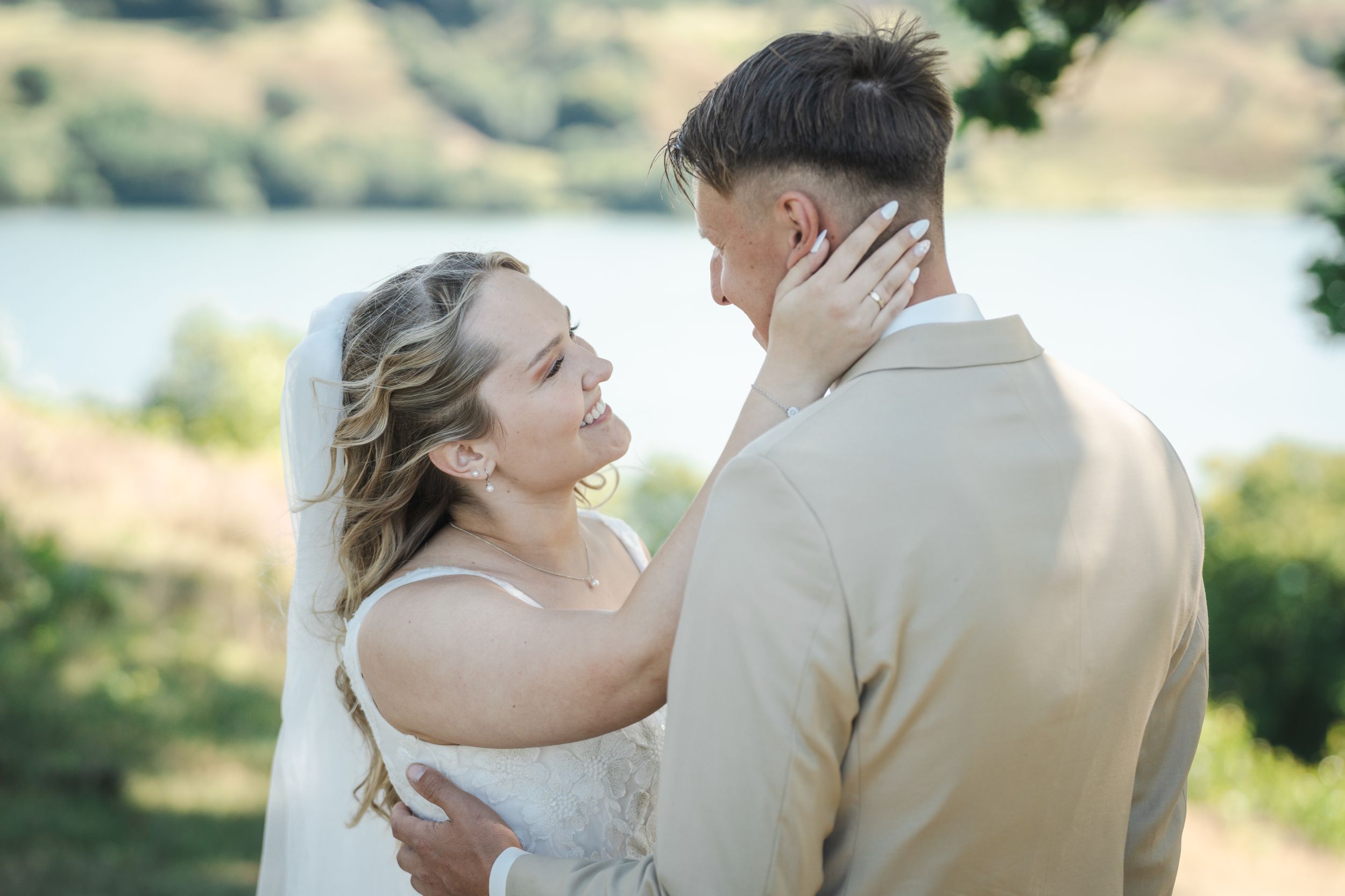 Romantic couple embraces in outdoor setting during golden hour lighting.