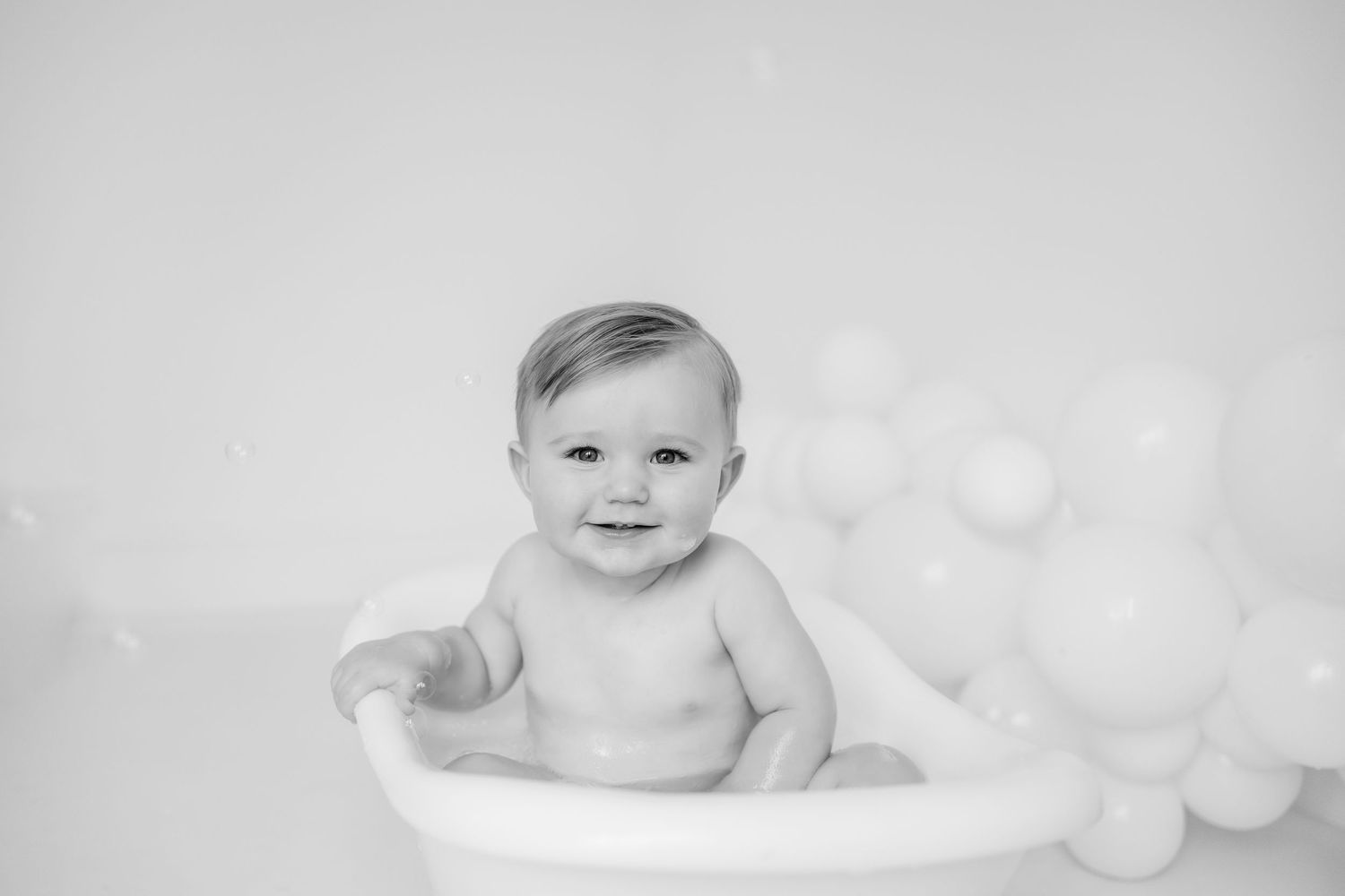 Black and white collage of baby portraits showing various expressions and poses on a light background.