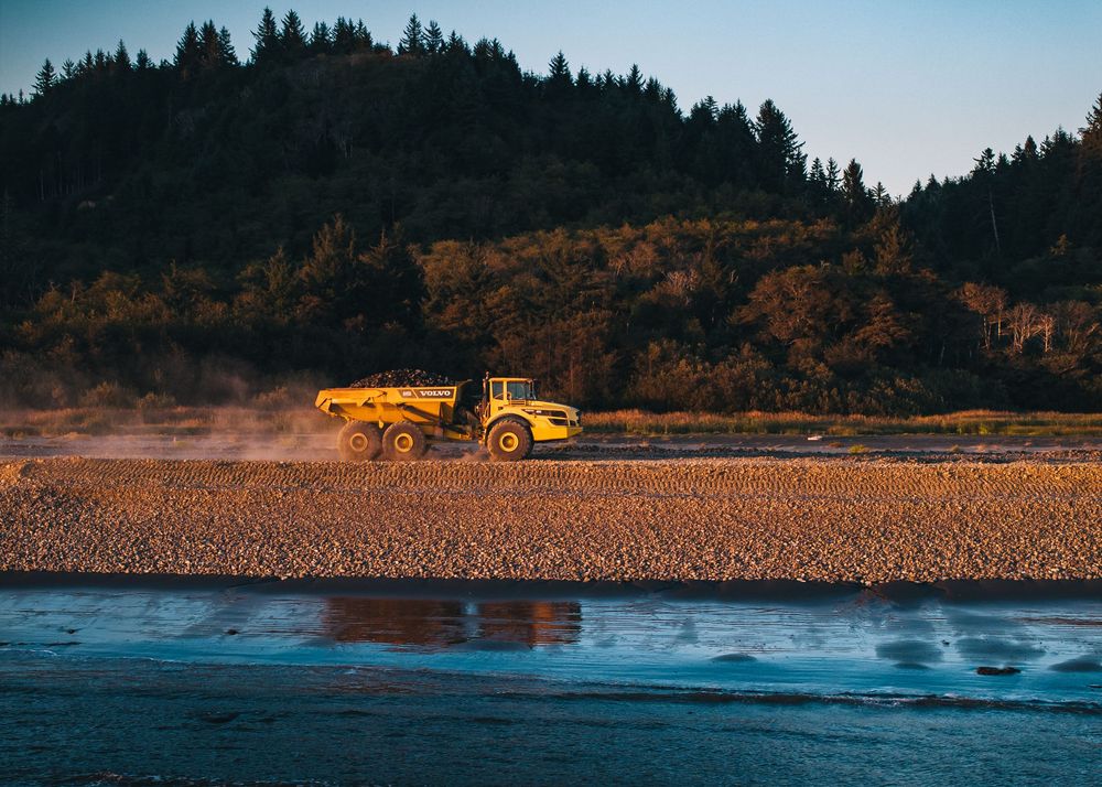 A series of landscape photos showing a yellow vehicle on a beach against a forested backdrop at different angles.