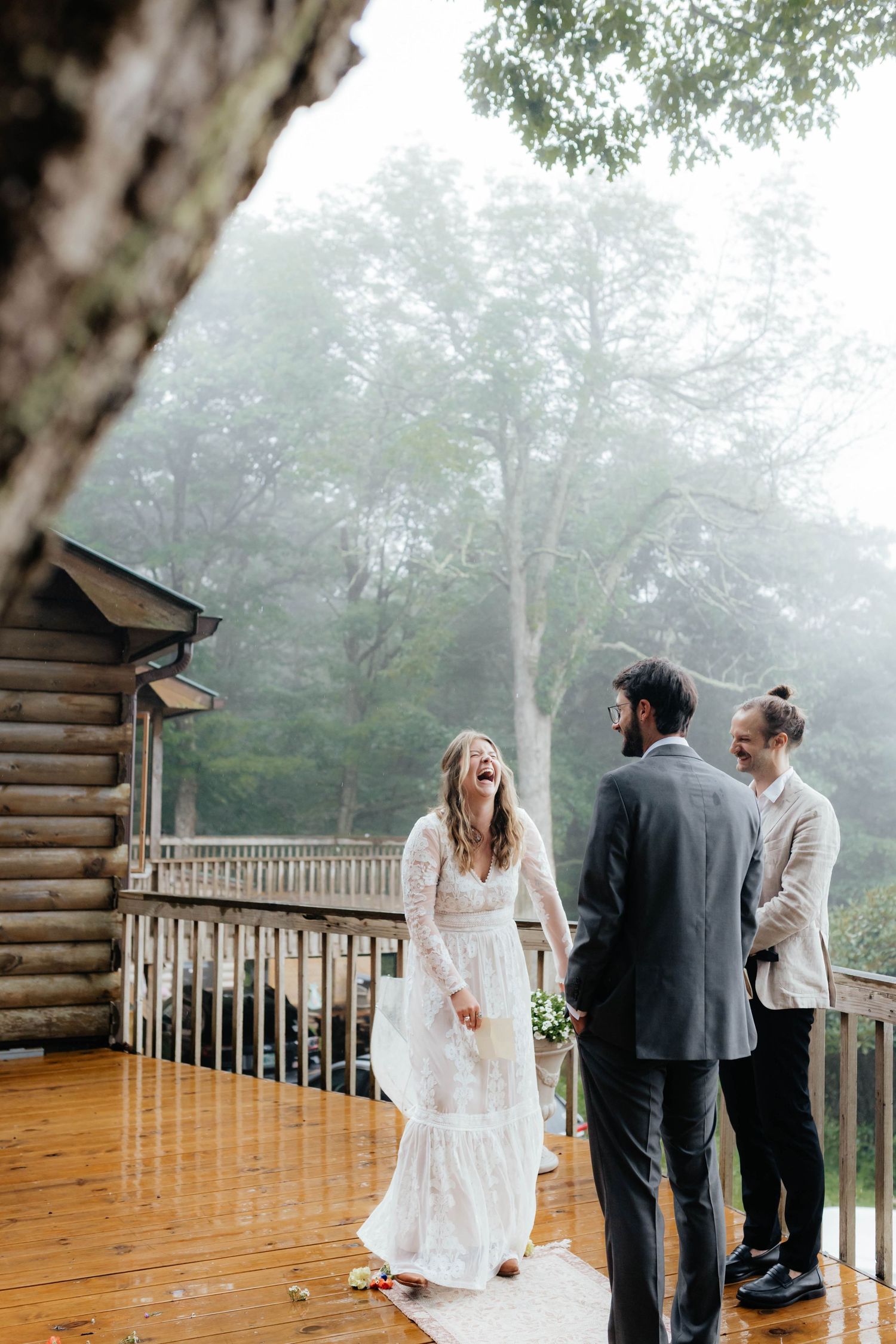 Misty morning wedding ceremony on rustic wooden deck surrounded by fog and forest.