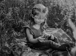 A black and white photo series showing someone picking flowers in a garden surrounded by lush foliage.
