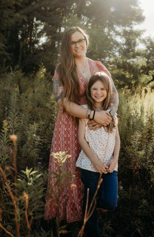 Mother and daughter share joyful moments together in a sunlit meadow during golden hour.
