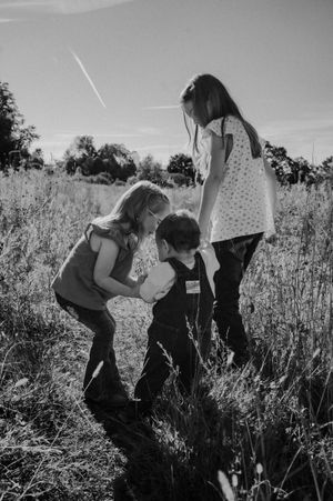 A sequence of black and white photos showing playful interactions in a wildflower meadow on a sunny day.