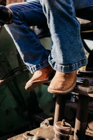 Close-up sequence of brown leather boots stepping on wooden pedals in a workshop setting.