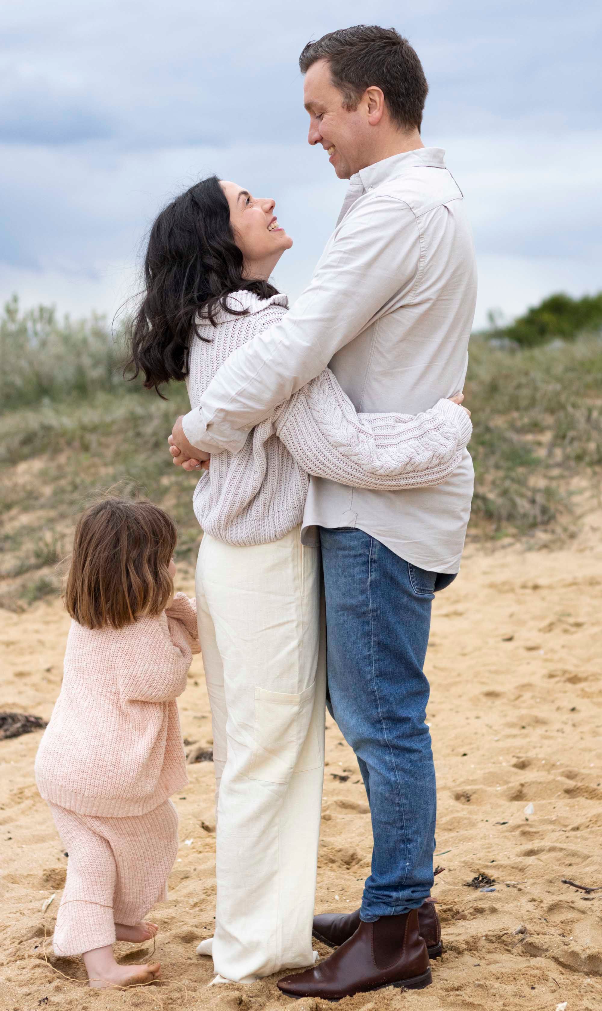 A family shares an intimate moment together on a sandy beach.
