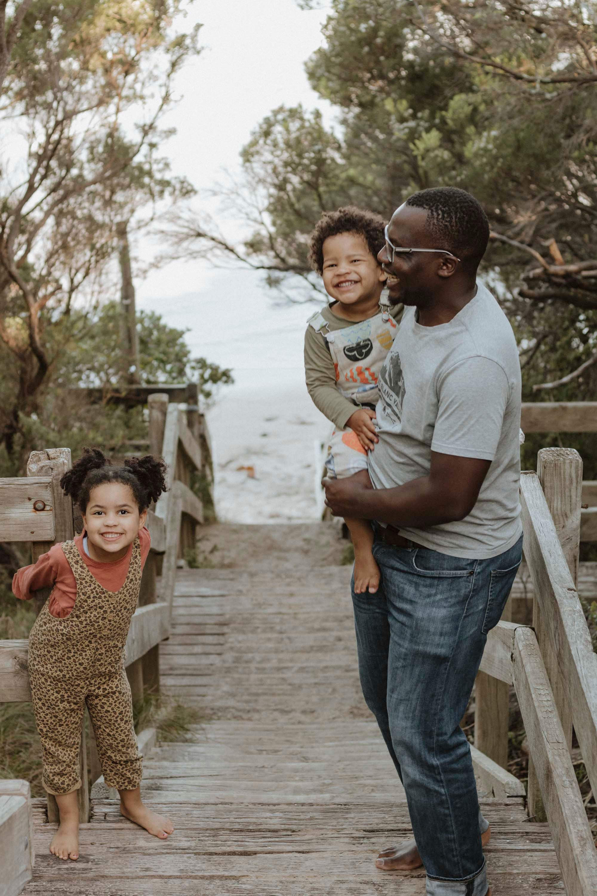 Family enjoying a playful moment together on wooden boardwalk steps at the beach.