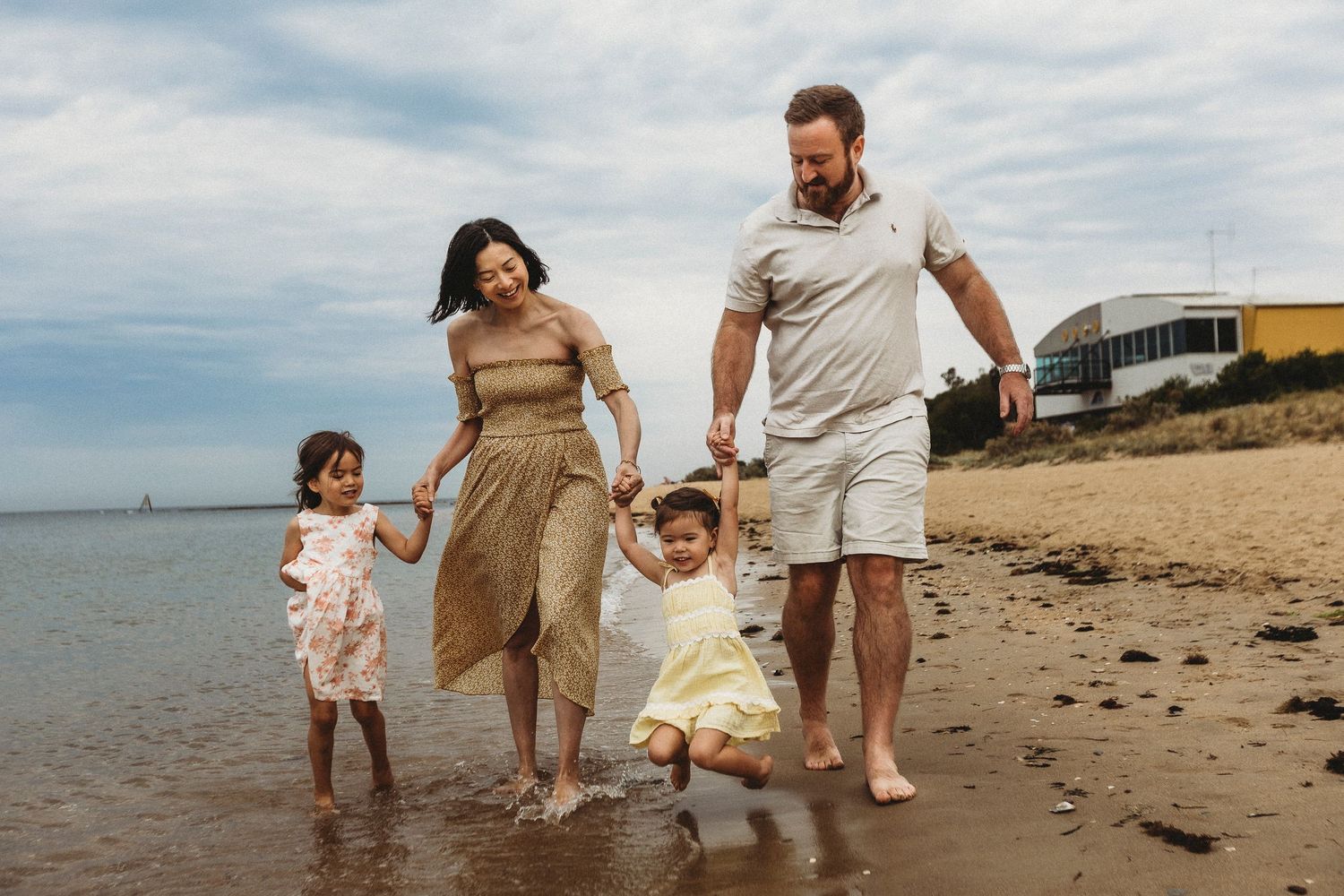 Family sharing warm embraces and laughter on sandy coastal dunes.