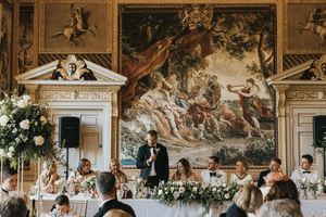 Elegant wedding celebration in an ornate Italian style ballroom with classical fresco paintings adorning the walls.