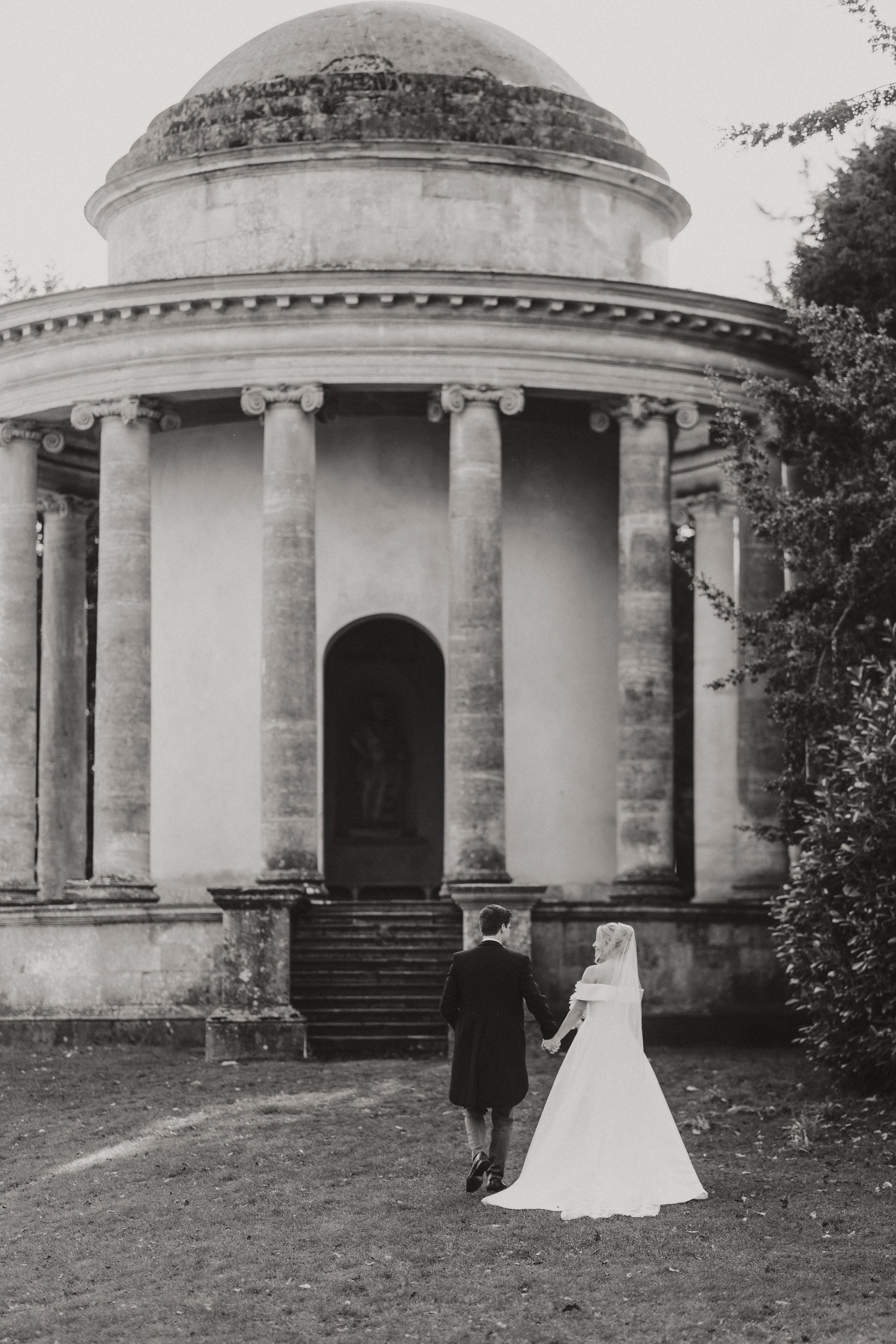 A black and white photo series of a classical columned stone structure with wedding couple figures in front of it.