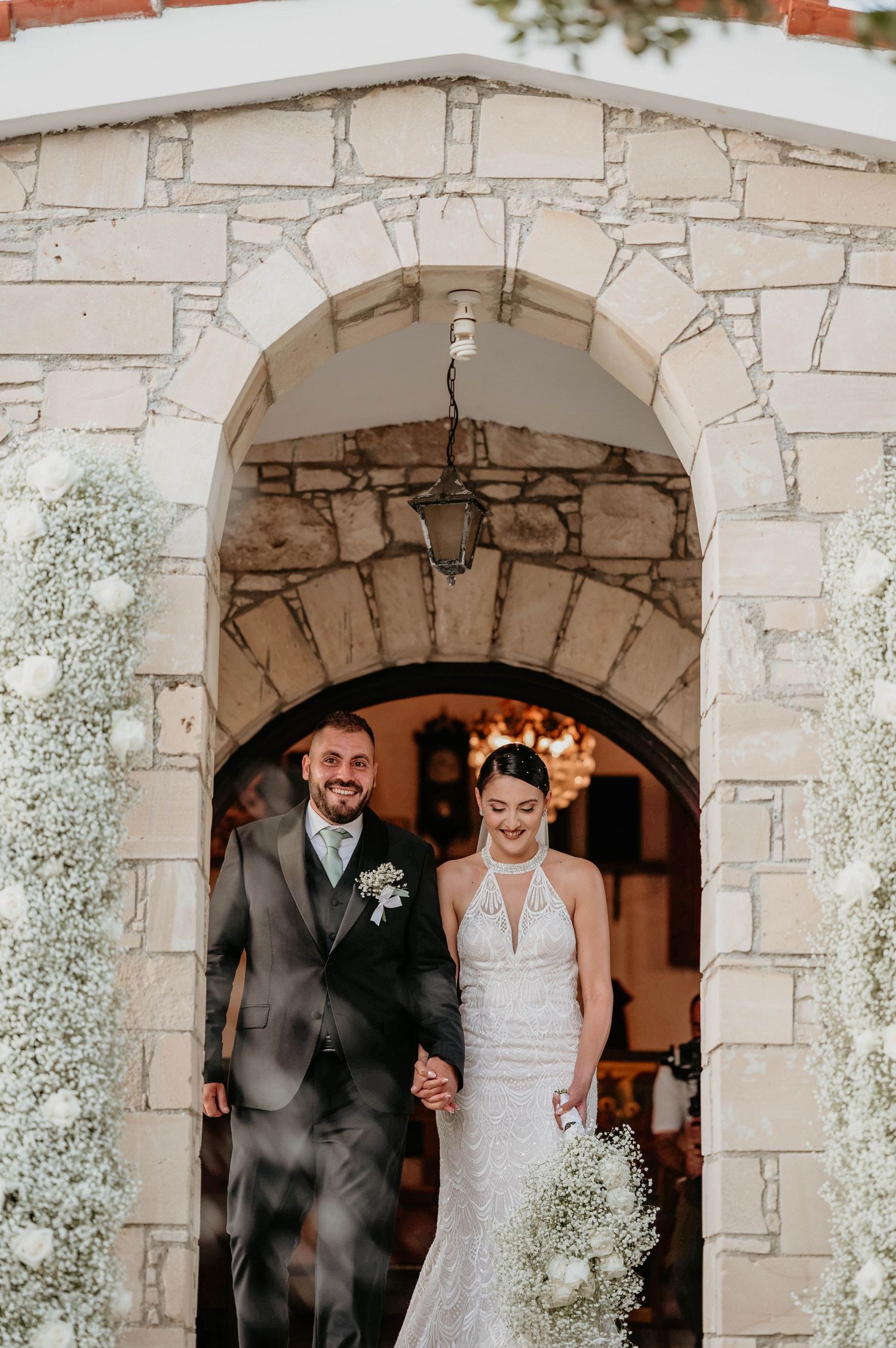 Romantic stone archway decorated with white baby's breath flowers for wedding ceremony.