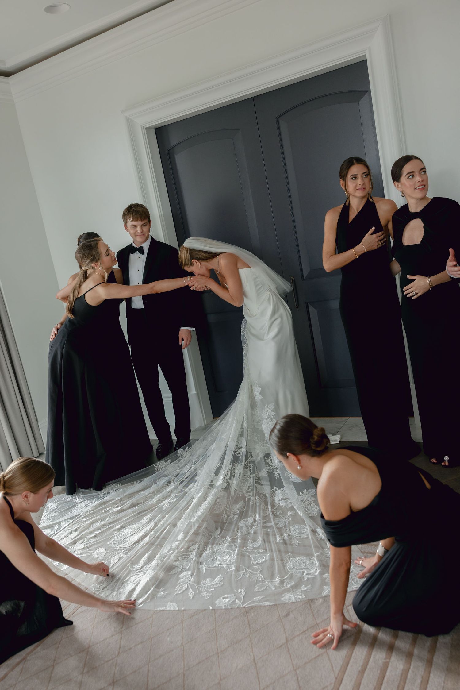 Wedding party helps arrange the bride's long flowing train and veil before the ceremony.
