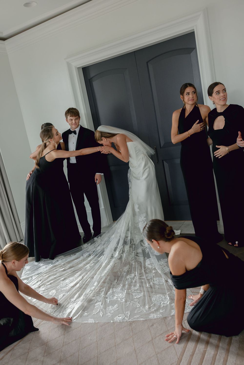 Wedding party helps arrange the bride's long flowing train and veil before the ceremony.