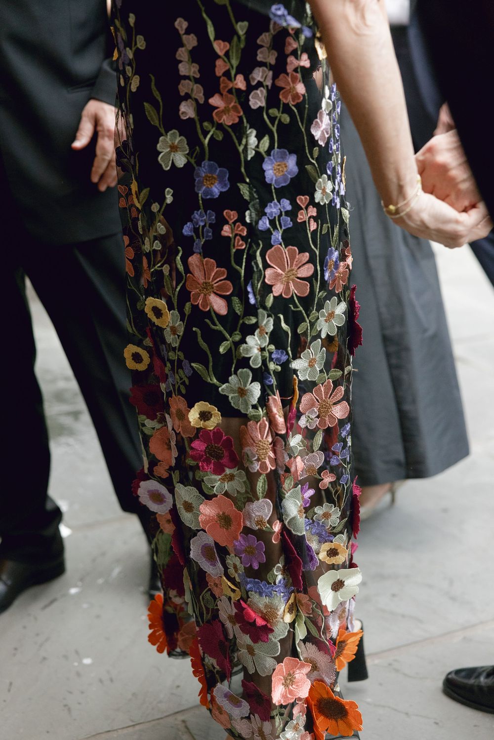 Close-up of an intricately embroidered floral dress with colorful blooms on dark fabric.