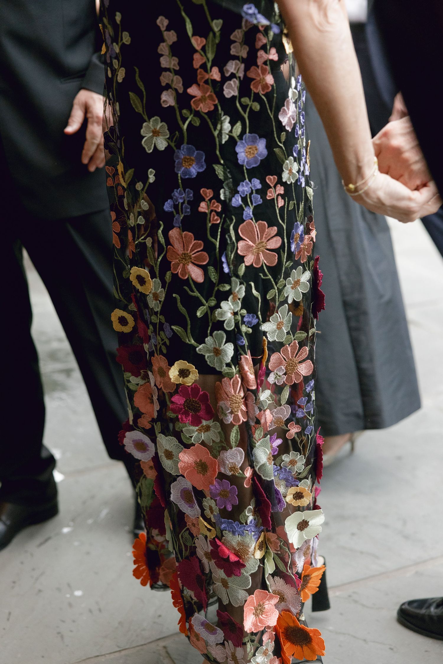 Close-up of an intricately embroidered floral dress with colorful blooms on dark fabric.