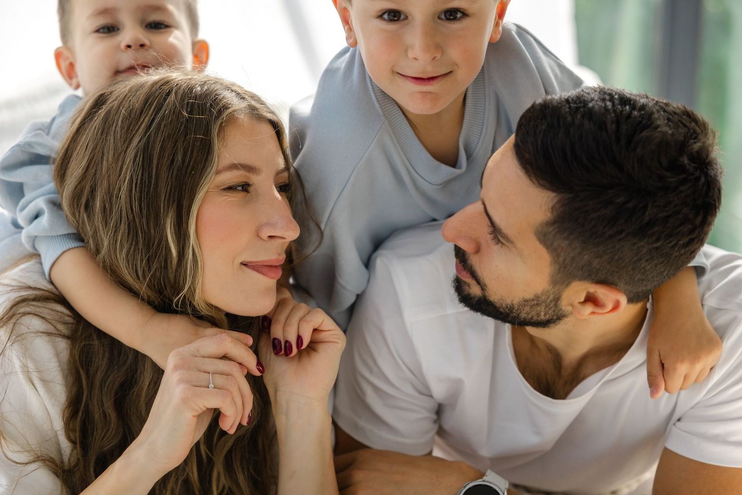 A loving family spending quality time together while relaxing on a white bed.