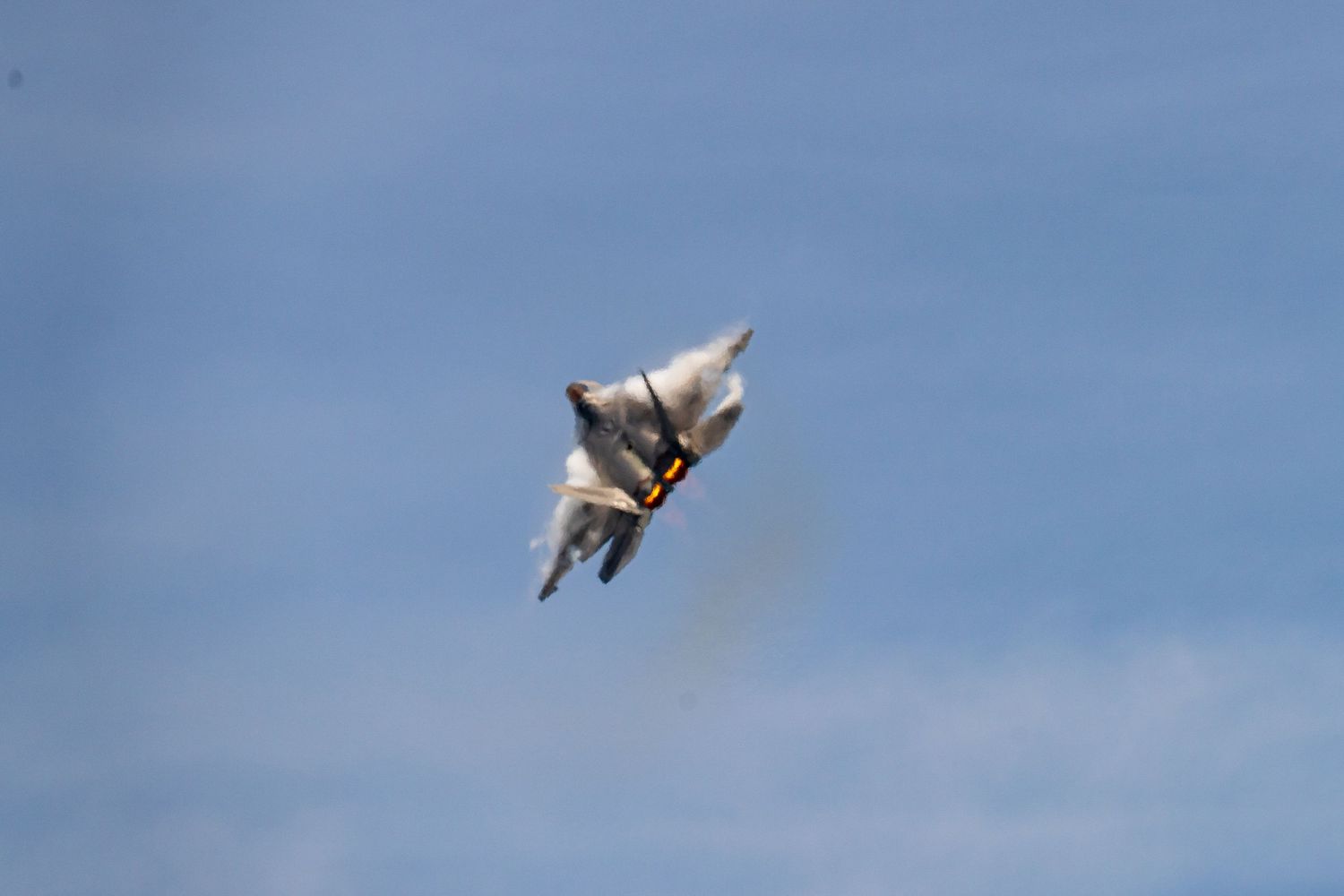 A series of photographs showing a fighter jet performing an arial maneuvers creating a vapor cone in blue sky at Cocoa Beach Air Show 2025