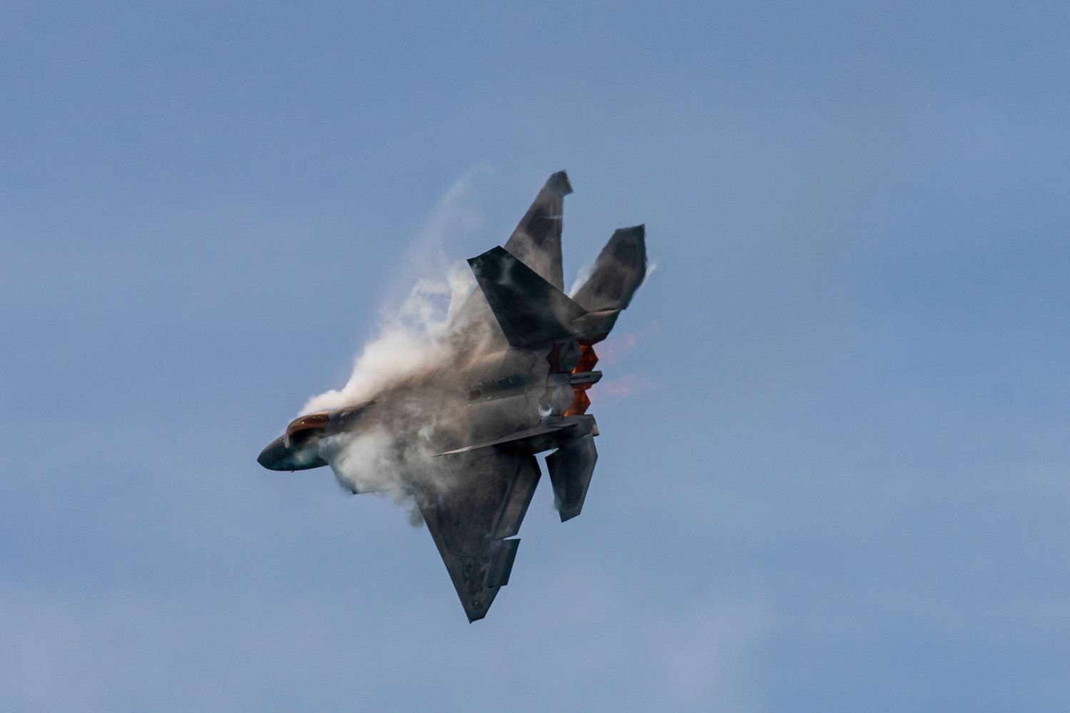 A series of photographs showing a fighter jet performing an inverted maneuver creating a vapor cone in blue sky at Cocoa Beach Air Show 2025