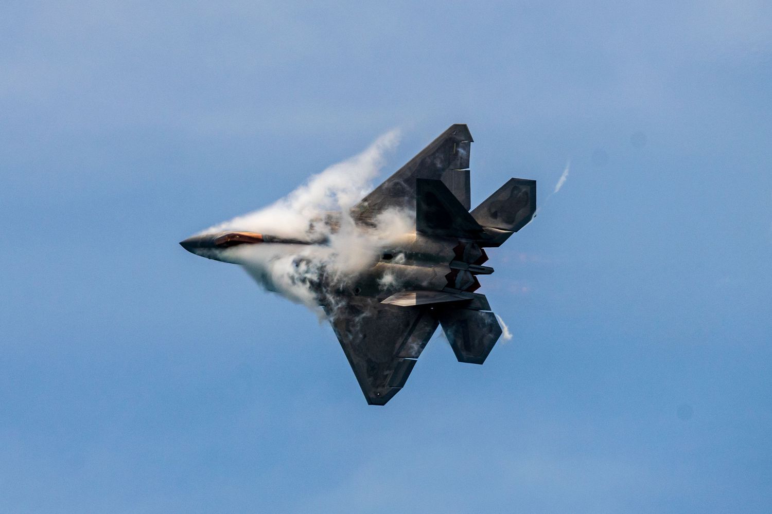 A series of photographs showing a fighter jet performing an inverted maneuver creating a vapor cone in blue sky at Cocoa Beach Air Show 2025