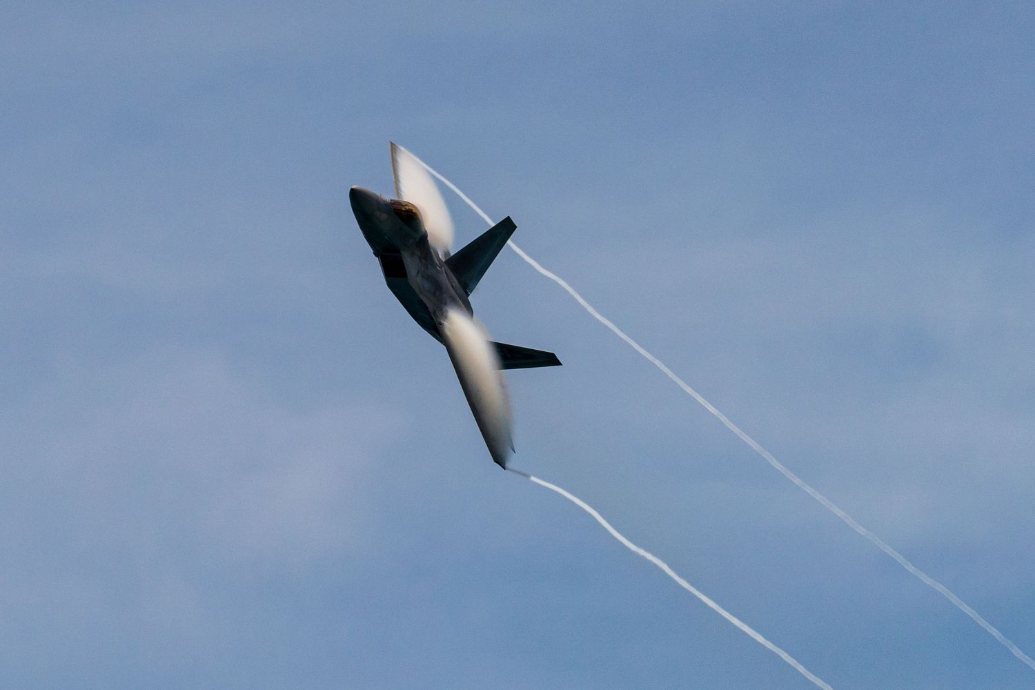 A series of photographs showing a fighter jet performing an inverted maneuver creating a vapor cone in blue sky at Cocoa Beach Air Show 2025