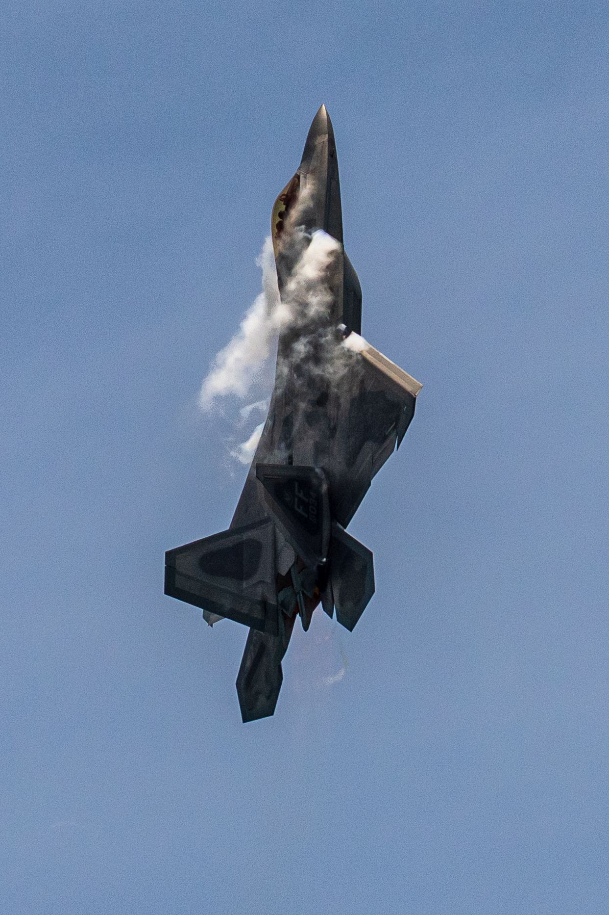 A series of photographs showing a fighter jet performing an inverted maneuver creating a vapor cone in blue sky at Cocoa Beach Air Show 2025