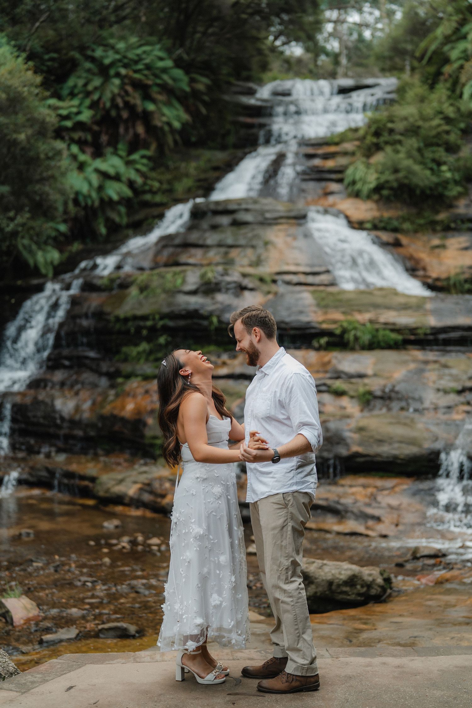 A tender moment captured against the backdrop of a scenic mountain waterfall.