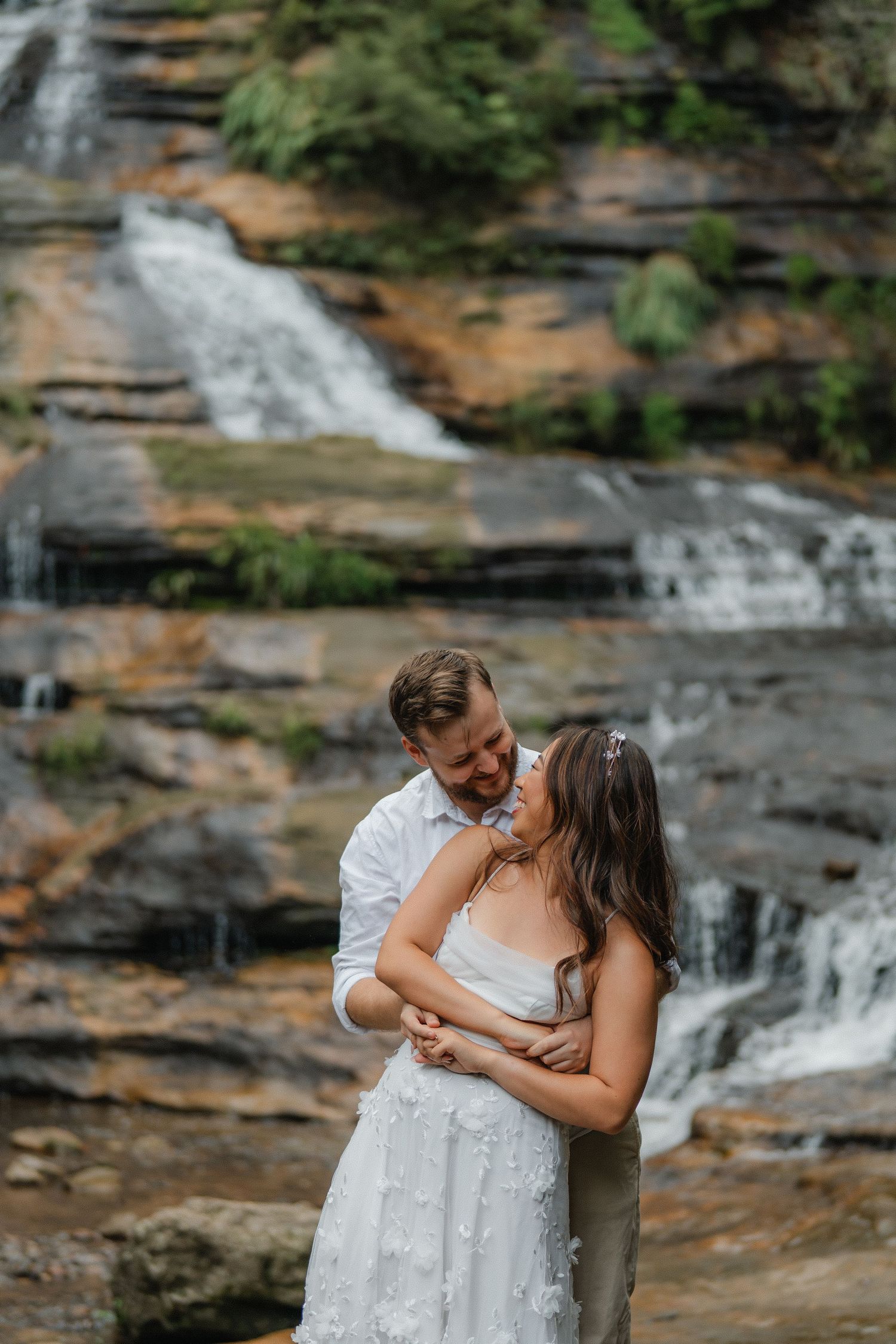 Couple shares intimate dance moves near a cascading waterfall.