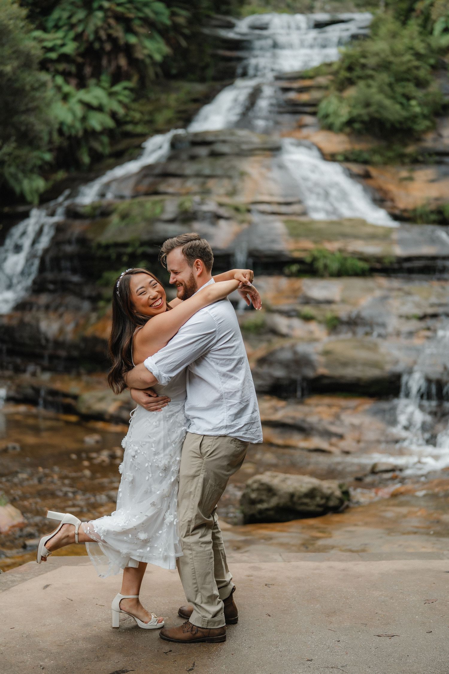 A romantic dance in front of a cascading waterfall with the couple wearing light summer attire.