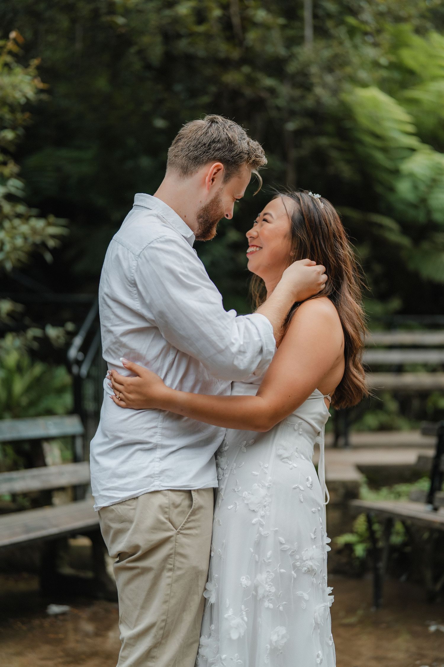A loving couple shares an intimate moment on a wooden deck surrounded by beautiful forest scenery.