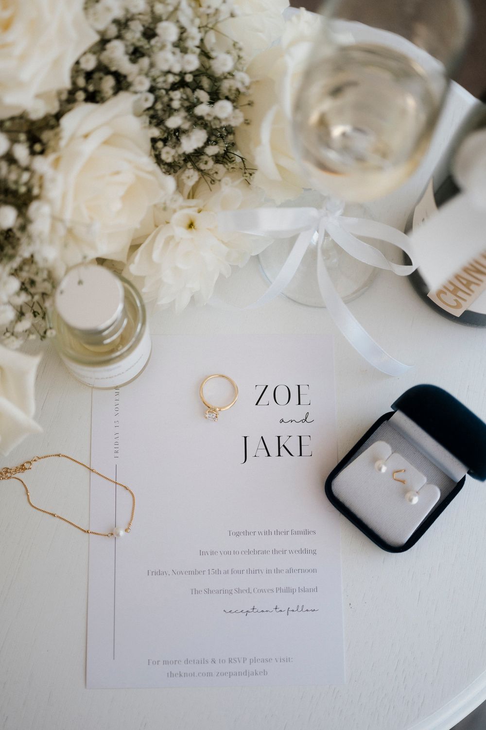 Wedding invitation with names Zoe and Jake displayed with rings and floral decorations.