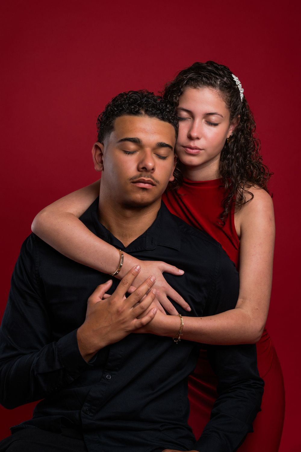 Two people embrace intimately against a deep red background in a series of romantic poses.