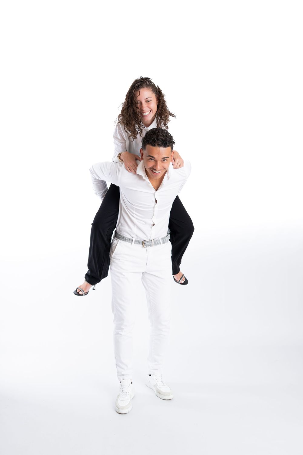 Dynamic fashion poses in all-white outfits against bright studio background.