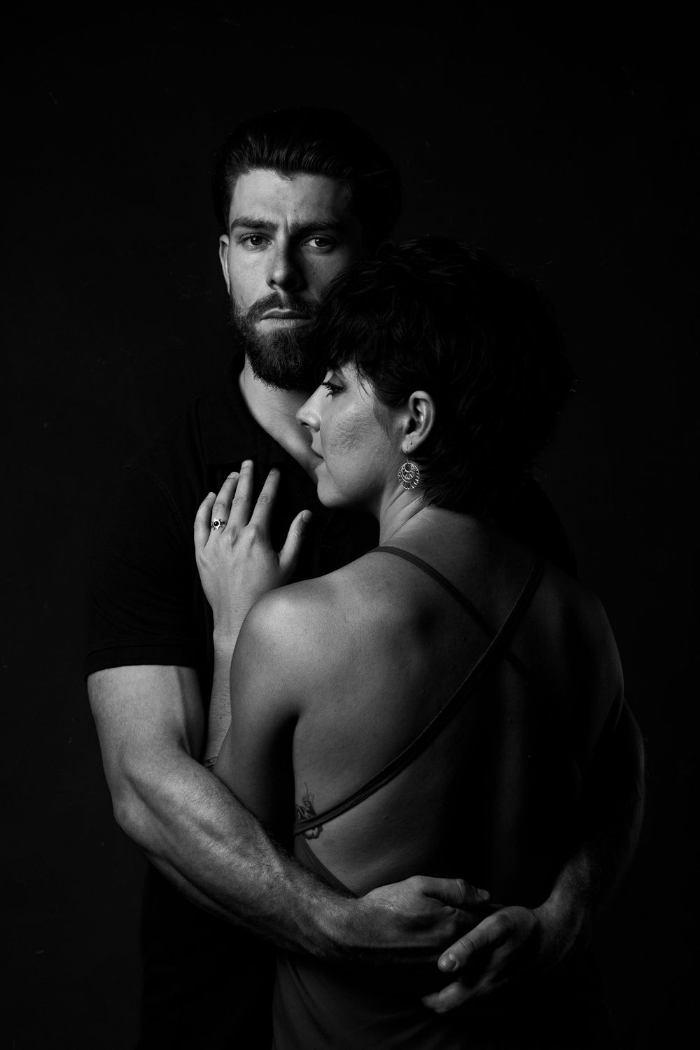 A series of dark monochrome artistic photographs showing intimate embraces between two individuals in shadow.