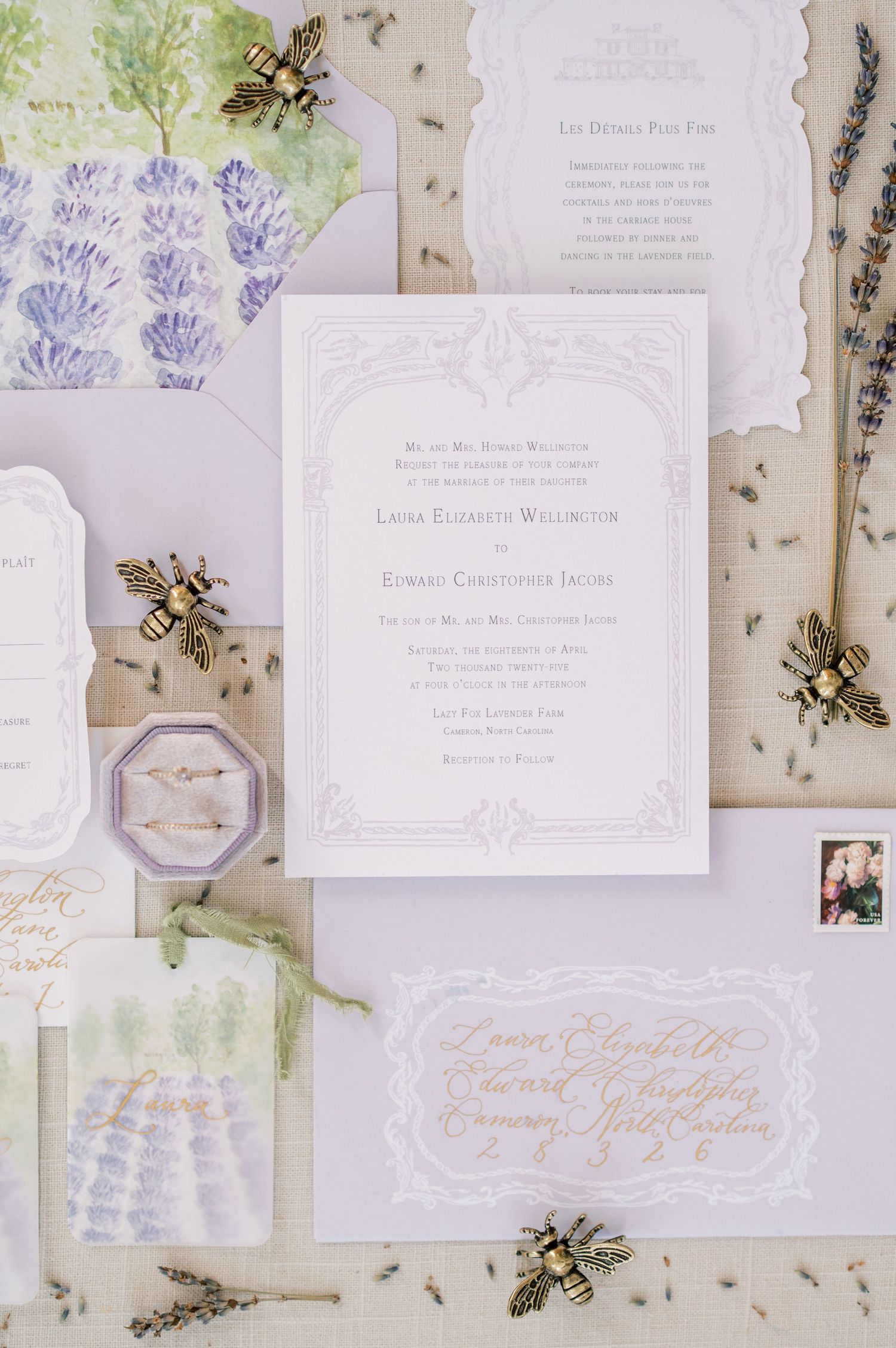 Elegant white and lavender wedding invitation suite with dried flowers and watercolor details laid on a light background.