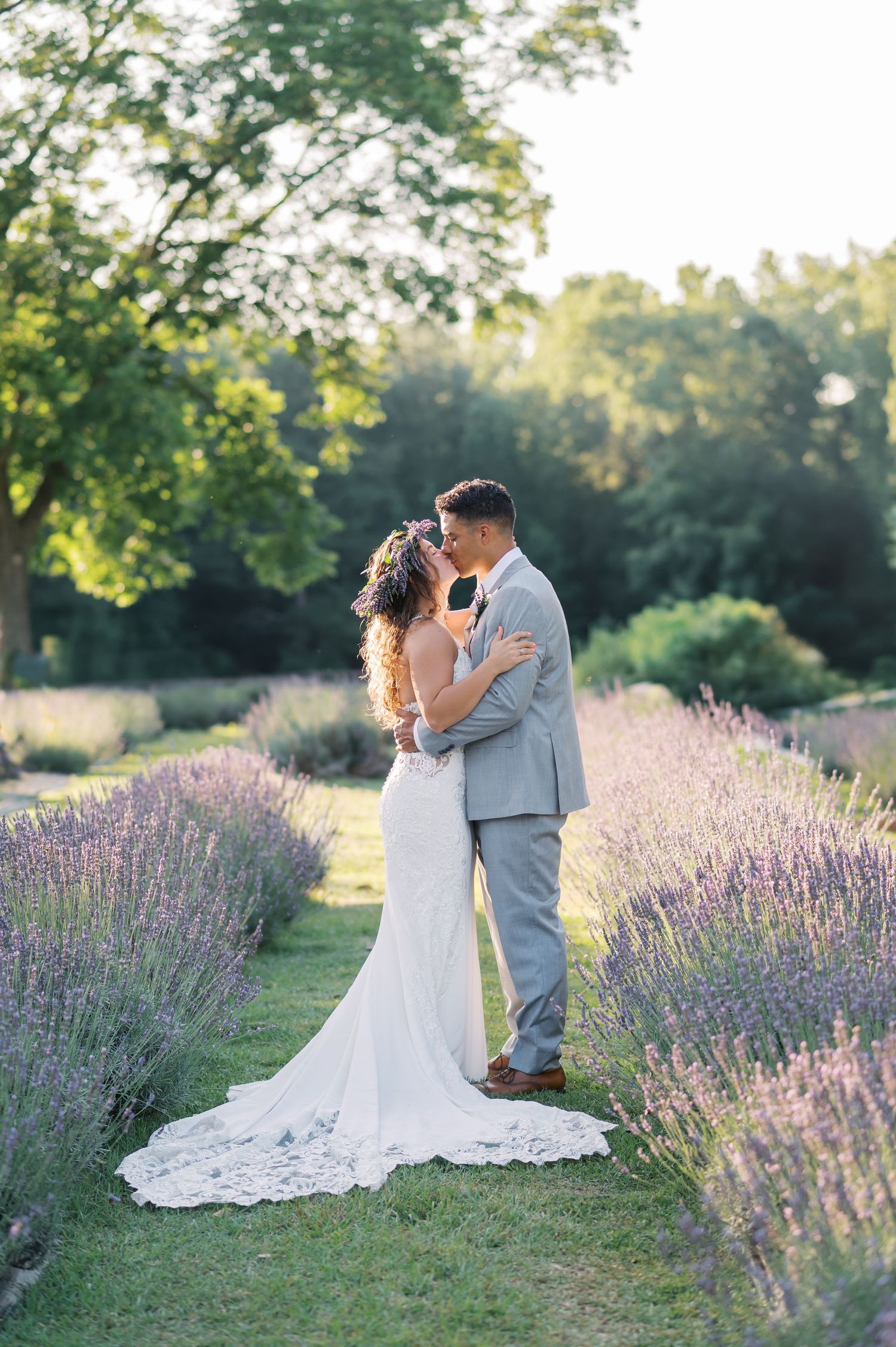 Newlywed couple shares romantic kiss in a serene lavender field during golden hour wedding near Fayetteville NC.