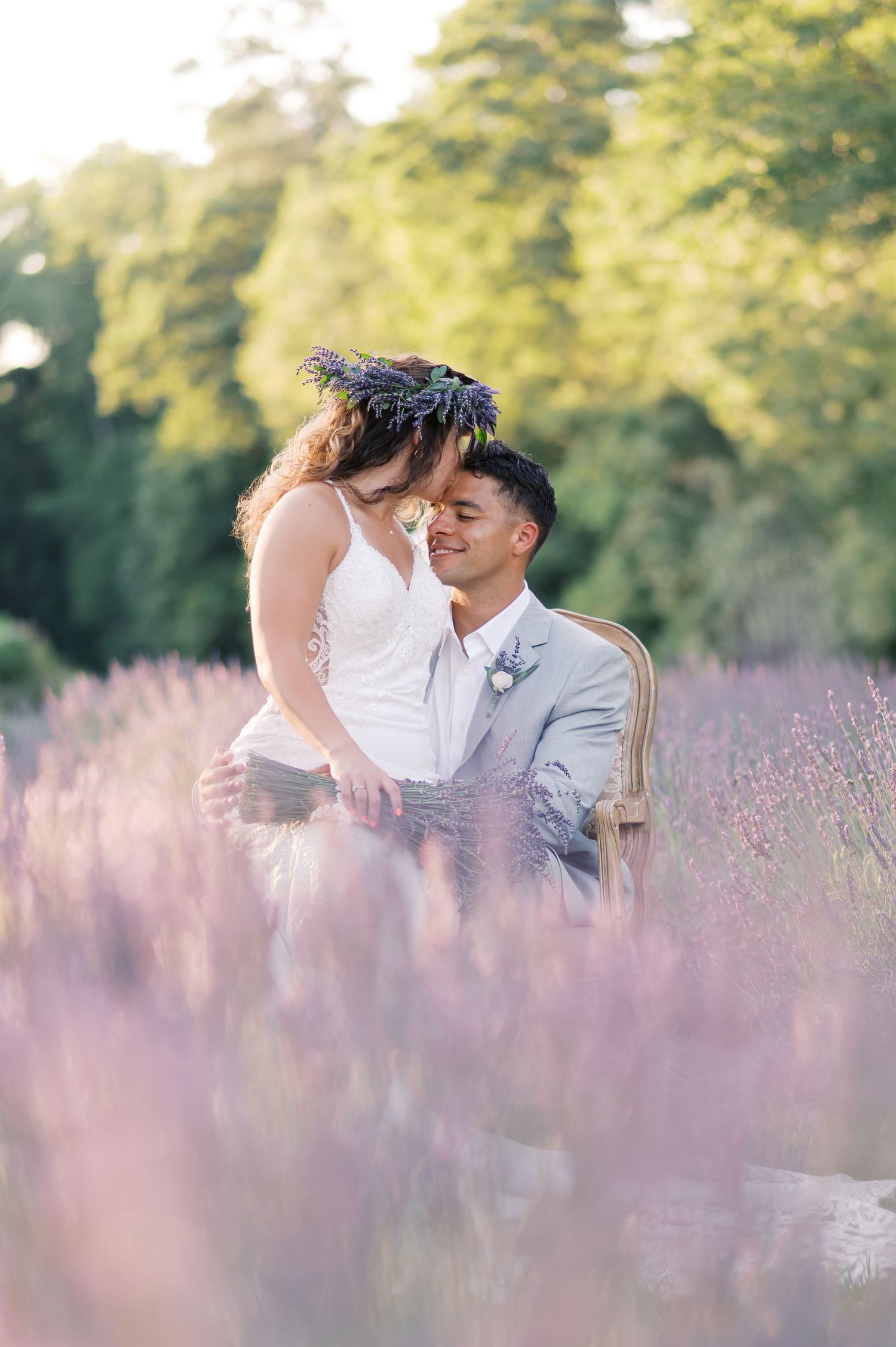 A romantic couple shares tender moments together while sitting in a blooming purple lavender field on a sunny day.