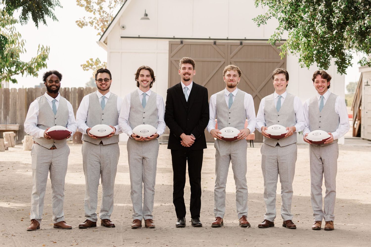 Groomsmen in light gray suits and dark suits stand together in a formal wedding party lineup.
